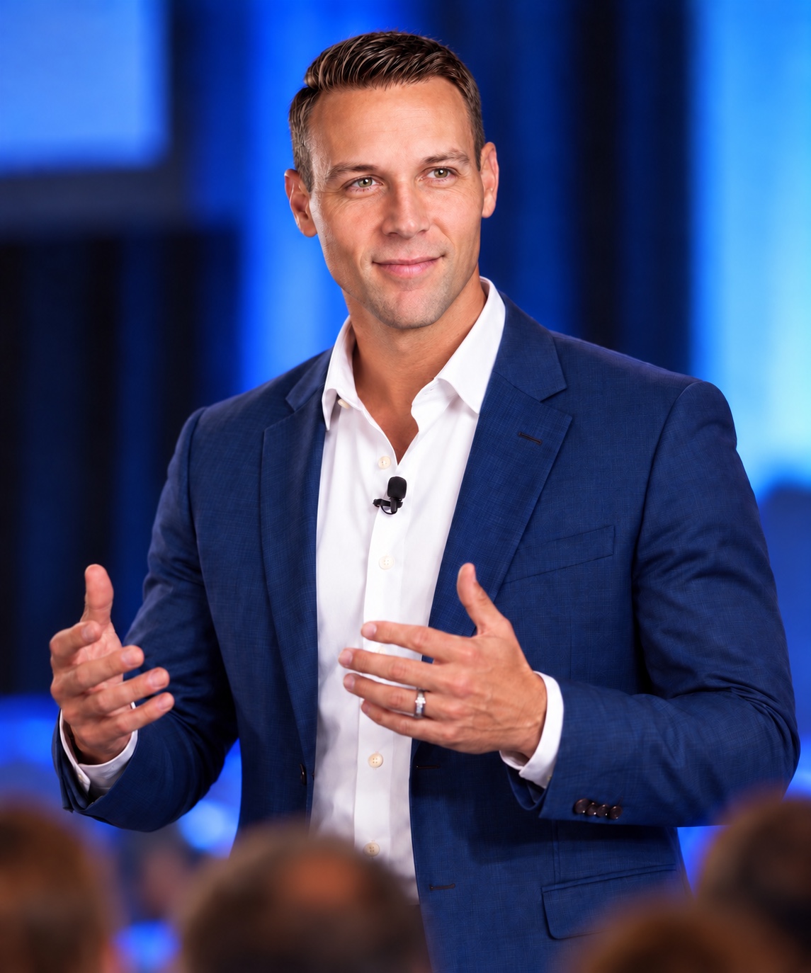 Tony Zinn speaking on stage in a navy suit
